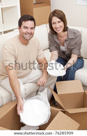 Happy couple in their thirties unpacking or packing boxes and moving into a new home.