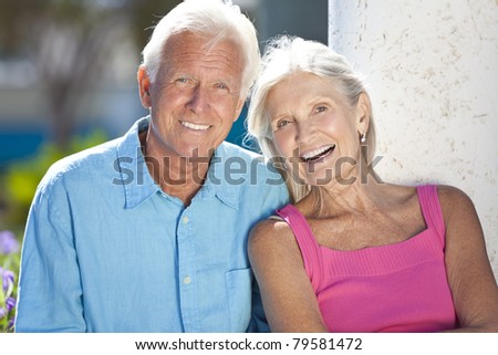 Happy senior man and woman couple sitting together outside in sunshine