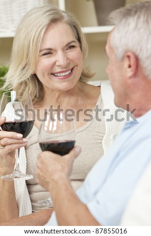 Happy senior man and woman couple sitting together at home smiling and drinking wine