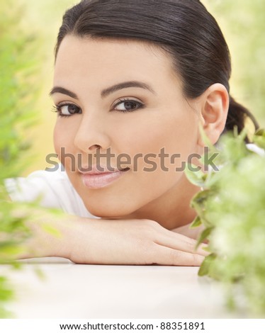 Spa concept beautiful Hispanic woman smiling surrounded in natural green leaves