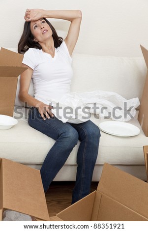 A beautiful single young woman tired and exhausted while packing or unpacking boxes and moving into a new home.
