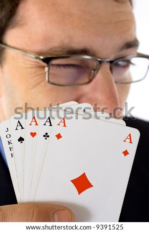 Winking man showing four aces and joker cards in foreground.