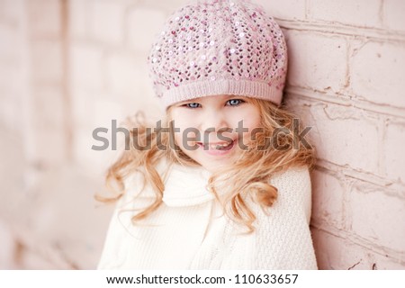 Portrait of an adorable toddler girl wearing fashion knitted clothes, a sweater and hat in pink and white