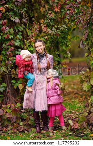 happy fashion family young beautiful mother and her two little daughter at autumn park