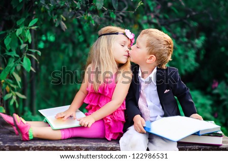 Adorable happy kids outdoors on summer day, little boy kissing a girl