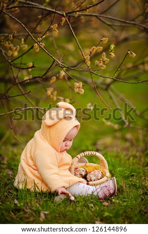 cute baby girl at bunny costume with easter cake and willow outdoor