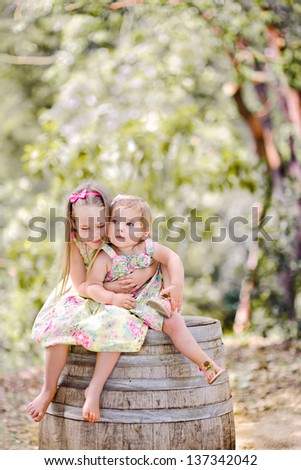 Two Young Girls Giving One Another Hug In Summer Field