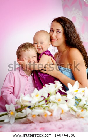 Happy family mother and her children boy and girl sitting indoor and smiling