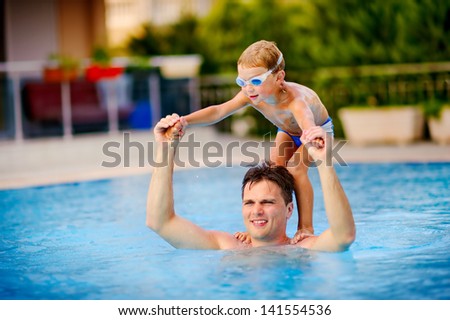 Young Swimmer Boy On Swim Start At Swimming Pool Ready For Jump Race And Win. Father Teach Her Son To Swim.