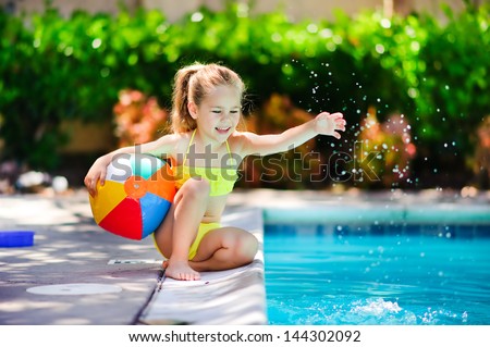 Smiling Toddler Girl Playing With Toy In Outdoor Swimming Pool