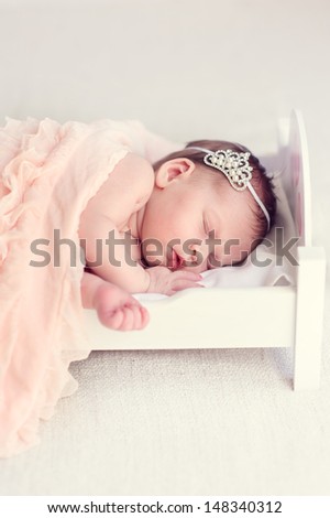 1 week newborn baby girl in crown sleeping at royal  miniature bed