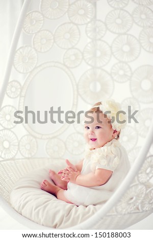Beautiful Cute Baby Girl In White Fashion Dress With Flower On Her Hair