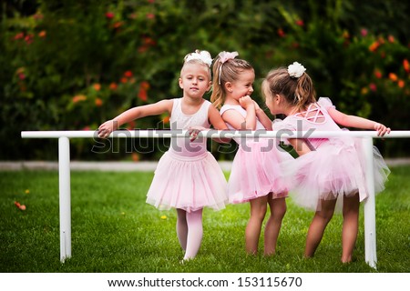 Group of little girls doing ballet bar exercises at beautiful summer garden background