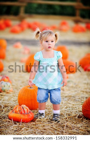 Happy baby girl picking a pumpkin for Halloween