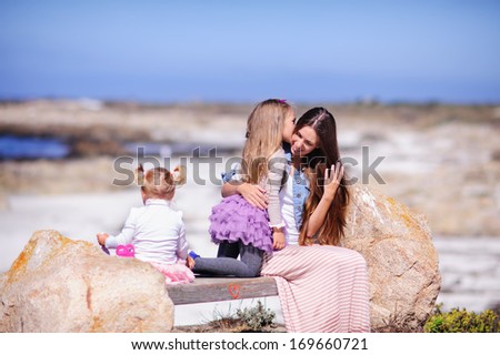 Family of three mother and two daughter have a rest on a sea shore
