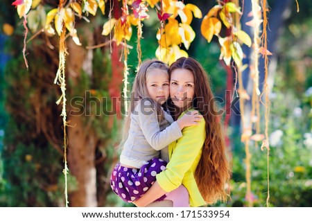 Happy young beauty mother and her daughter in fashion casual wear at green nature background