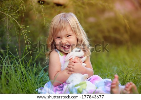 Cute little girl with a bunny rabbit has a easter at green grass background