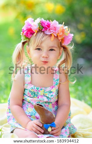 happy easter child  girl eat chocolate bunny at meadow background