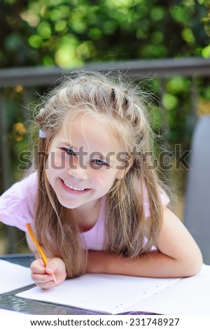 Little adorable happy girl making school homework outdoor