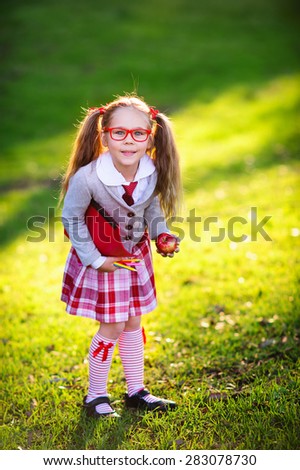 Happy little schoolgirl with lunch, book and pencils. Back to school outdoor