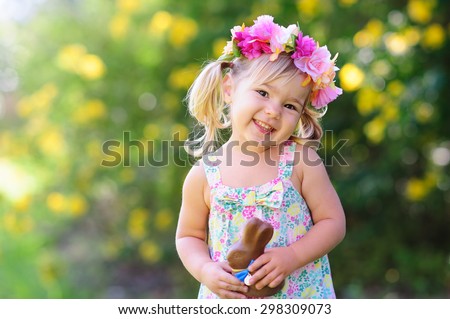 happy easter girl eat chocolate bunny at meadow background