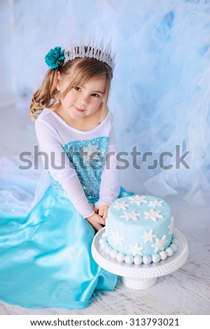 Little princess girl on a styled Frozen birthday party with snowflakes cakes