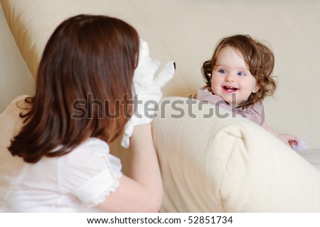 Beautiful mother plays a puppet show with a baby-daughter