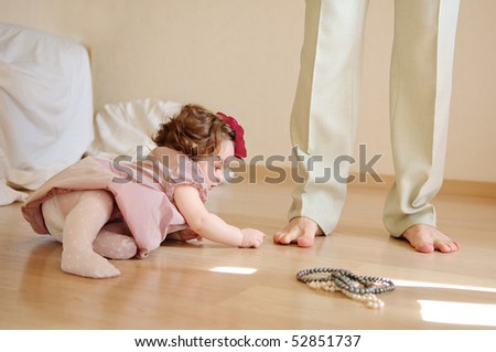 9-months baby-girl lies on a floor and plays with feet of the daddy