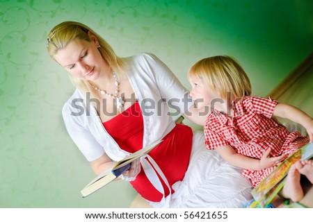 Mother and daughter sit on a floor and read the books and tell fairy tales