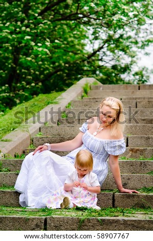 beautiful woman and her adorable baby daughter sit on a stone steps