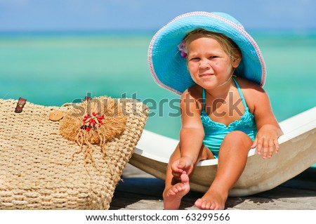 cute small girl in big hat and bikini relax at turquoise ocean background