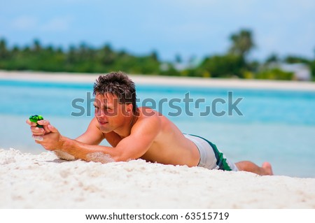 athletic man playing with toy water guns on exotic beach