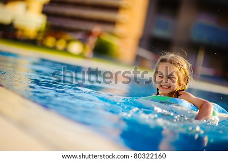 Pretty little girl swimming in outdoor pool and have a fun with inflatable circle