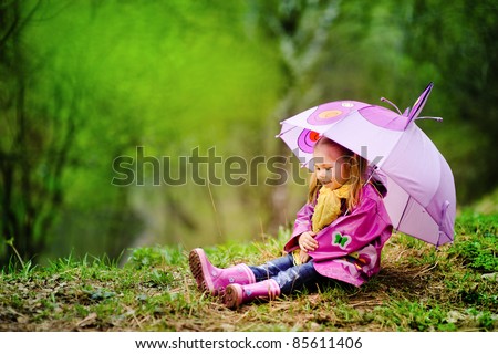 smiling little girl with umbrella in raincoat and boots outdoor