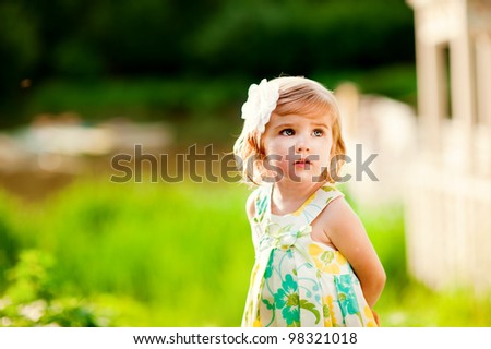 Beautiful little girl with flower on her head outdoors in sunny day