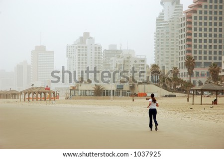 Woman running on empty winter beach in bad weather