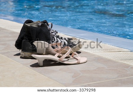 Two pairs of old shoes on edge of a pool