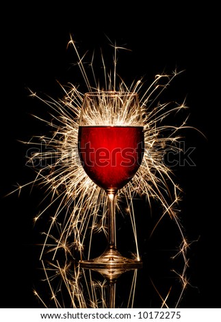 Glowing red wine glass and firework on black background