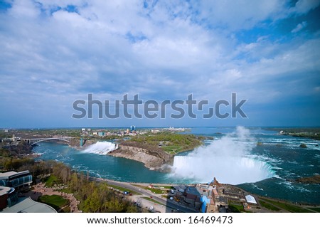 Wide panorama of Niagara falls wonder at spring under dramatic sky with city of Buffalo in background