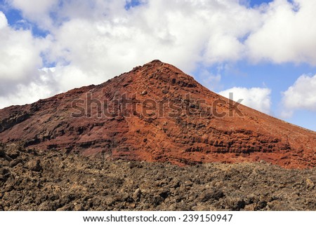 Red volcano with solidified lava in the foreground in Lanzarote, Canary islands, Spain