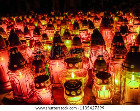 Many glass votive candles lit in the dark