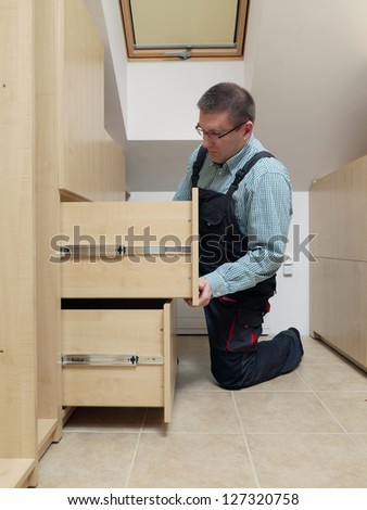 Carpenter installing wardrobe drawers in walk-in closet