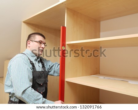Carpenter assembling wardrobe furniture in walk-in closet
