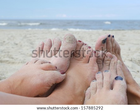 Group of male and female playful feet on the beach with the sea in the background