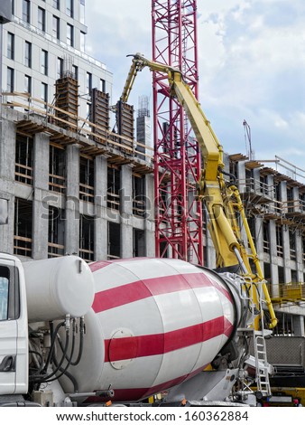 Highrise building under construction and ready mix concrete pump delivering concrete up above