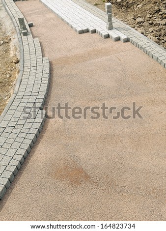 Unfinished pavement path being laid from concrete pavement blocks with mineral topping
