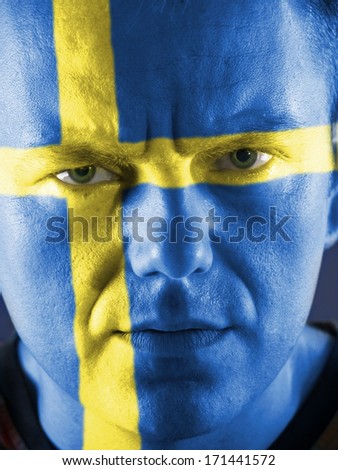 Closeup of young Swedish supporter face painted blue with yellow cross