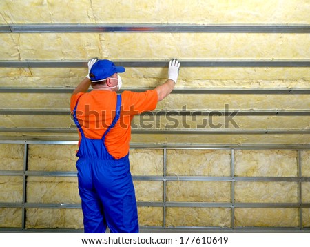 Construction worker thermally insulating house attic with mineral wool