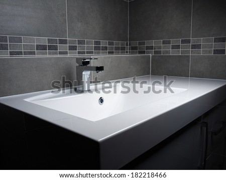 Modern bathroom washbasin with chrome faucet and gray tiling