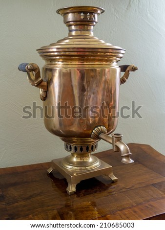 Old Russian tea brewing samovar standing on wooden tea table